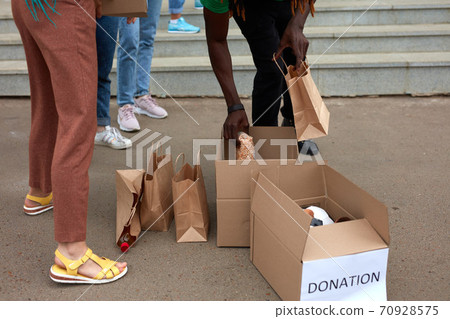 group of diverse people sort through donated food items while volunteering in community group of diverse people sort through donated food items while volunteering in community 70928575