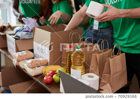 group of diverse people sort through donated food items while volunteering in community 70929168