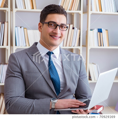 Businessman with a laptop working in the library 70929169