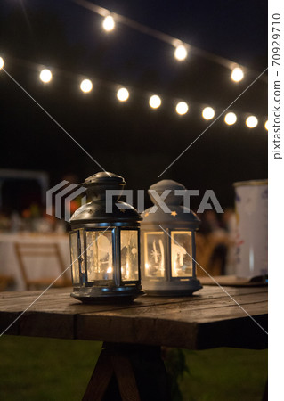 Lanterns on a wood table on an outdoors wedding banquet 70929710