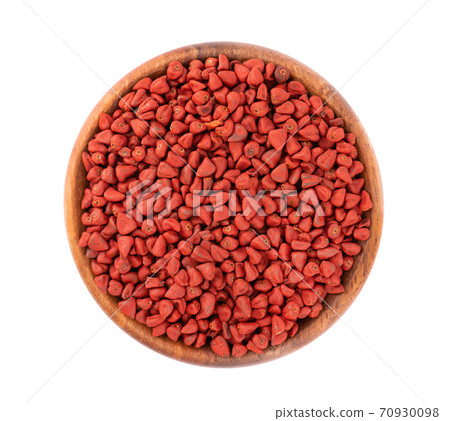 Annatto seeds in wooden bowl, isolated on white background. Achiote seeds, bixa orellana. Natural dye for cooking and food. Top view. 70930098