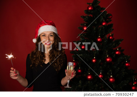 Cheerful woman in santa hat celebrating New Year, Christmas on red background Cheerful woman in santa hat celebrating New Year, Christmas on red background 70930247