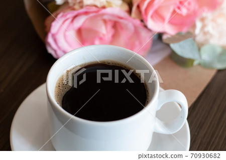 A cup of black hot coffee and a lovely bouquet of roses A cup of black hot coffee and a lovely bouquet of roses 70930682