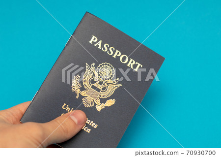 Hand holding US Passport on blue background Hand holding US Passport on blue background 70930700