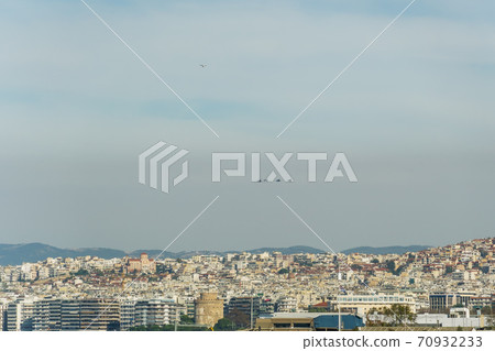 F-16 fighter jets flying above a city landscape.  70932233