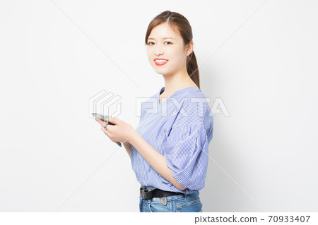 A young woman using a smartphone 70933407