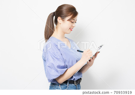 Young woman writing notes on the clipboard 70933919