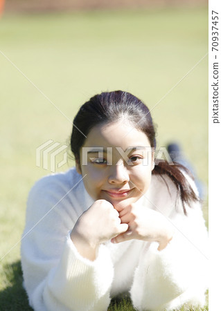 Young woman relaxing with a smile looking at the camera Young woman relaxing with a smile looking at the camera 70937457