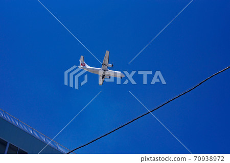 Landing propeller airliner flying low over the city 70938972
