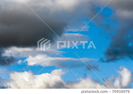 White clouds and dramatic dark thunderclouds floating across blue sky to change season weather 70938976
