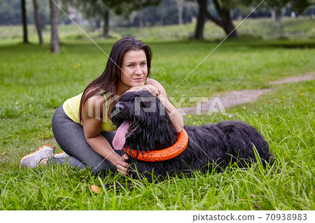 Woman hugs black briard during walking on open air in park. Woman hugs black briard during walking on open air in park. 70938983