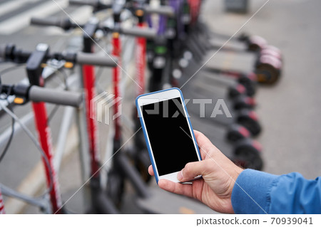 Electric scooter rental via smartphone app with help of QR code. Electric scooter rental via smartphone app with help of QR code. 70939041