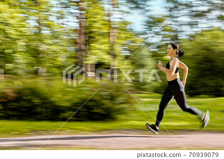 Blurred motion of woman who runs in city garden at summer. Blurred motion of woman who runs in city garden at summer. 70939079