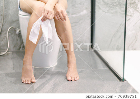 Closeup woman sitting on toilet in the morning with depressed feeling, selective focus Closeup woman sitting on toilet in the morning with depressed feeling, selective focus 70939751