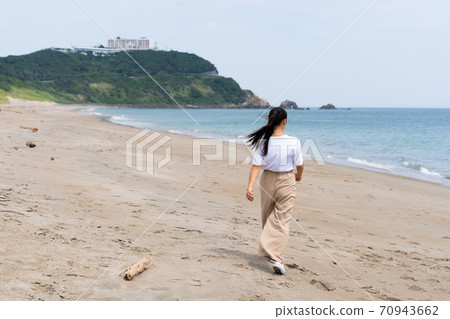 一個女人在沙灘上散步 70943662