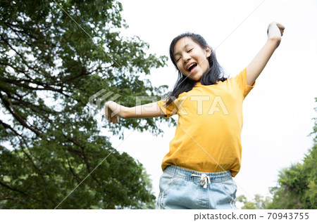Happiness asian woman standing feel comfortable at park,smiling female teenage with stretching her arms,enjoy breathing fresh air,freedom and relaxing in green nature after school,lifestyle concept 70943755