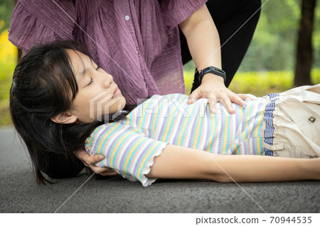 Sick daughter is fainted and fallen on floor while playing and exercise,asian mother help,take care, child girl with congestive heart failure,female unconscious fell to the ground suffer heart attack 70944535