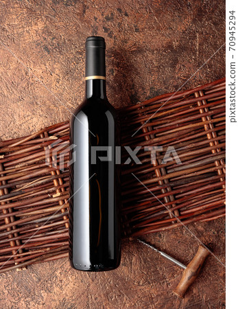 A bottle of red wine on an old rough background. A bottle of red wine on an old rough background. 70945294