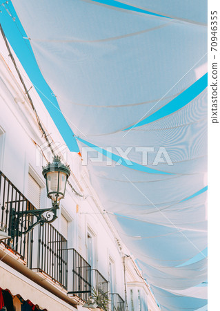 Nerja, Spain. White Cloth Is Stretched Between Houses On Old Narrow Street Nerja, Spain. White Cloth Is Stretched Between Houses On Old Narrow Street 70946355