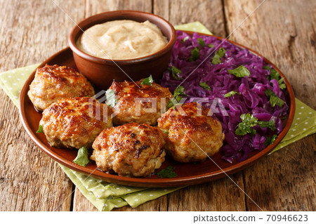 Delicious fried meatballs with hot stewed red cabbage and sauce close-up in a plate. horizontal 70946623
