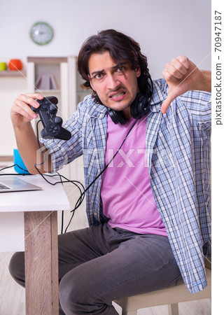 Young male student playing computer games at home Young male student playing computer games at home 70947187