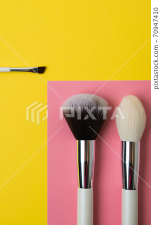 makeup brushes on a multi-colored background, pink and yellow makeup brushes on a multi-colored background, pink and yellow 70947410