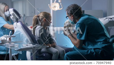 Orthodontist explaining teeth structure to little girl Orthodontist explaining teeth structure to little girl 70947940