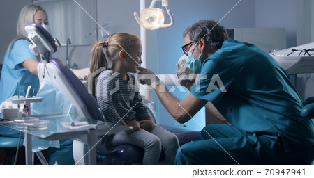 Orthodontist explaining teeth structure to little girl Orthodontist explaining teeth structure to little girl 70947941
