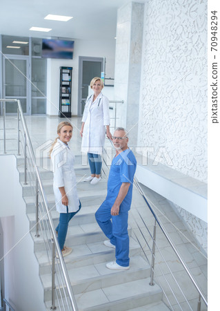 Team of smiling medical workers going upstairs Team of smiling medical workers going upstairs 70948294