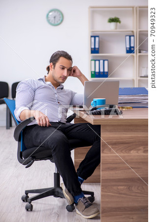 Young male bookkeeper working in the office Young male bookkeeper working in the office 70949323