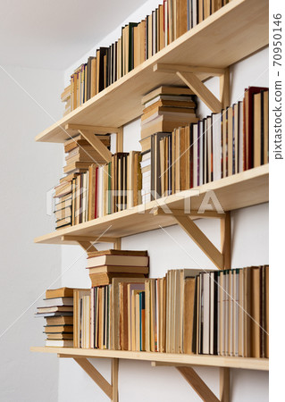 Bookshelves with hardback overturned books 70950146