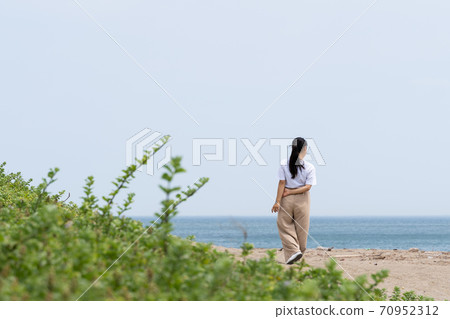 一個女人在沙灘上散步 70952312