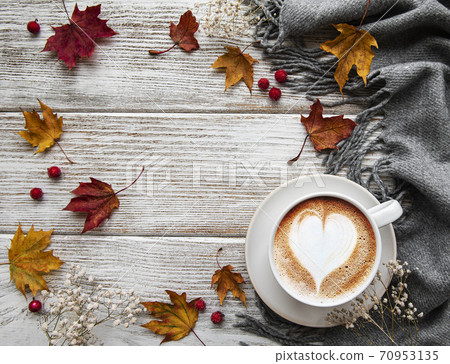 Cup of coffee and dry leaves on white wooden background 70953135