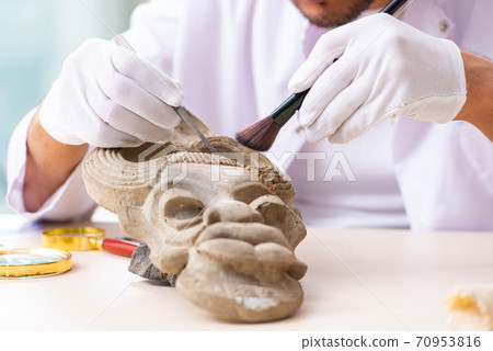 Young male archaeologist studying ancient african stonemask Young male archaeologist studying ancient african stonemask 70953816