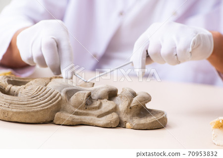 Young male archaeologist studying ancient african stonemask Young male archaeologist studying ancient african stonemask 70953832