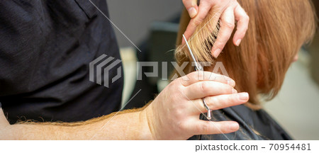 Hairdresser cuts hair to young woman 70954481