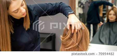 Hairdresser checks hairstyle of woman Hairdresser checks hairstyle of woman 70954482