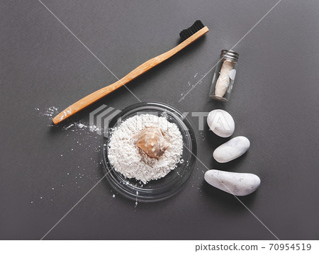 A bamboo toothbrush with a floss and toothpowder decorating with a shell. A bamboo toothbrush with a floss and toothpowder decorating with a shell. 70954519