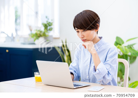 A middle-aged woman teleworking in the living room. A middle-aged woman teleworking in the living room. 70954709