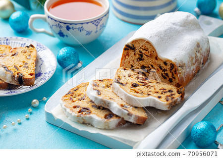 Christmas stollen. Traditional German festive dessert with cup of tea. Blue background. Close up. Christmas stollen. Traditional German festive dessert with cup of tea. Blue background. Close up. 70956071