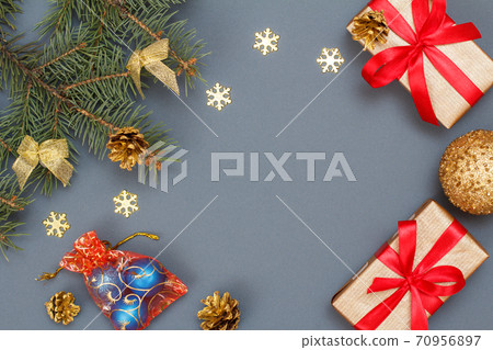 Gift boxes, fir tree branches with cones and toys on gray background Gift boxes, fir tree branches with cones and toys on gray background 70956897