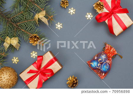 Gift boxes, fir tree branches with cones and christmas toys on gray background Gift boxes, fir tree branches with cones and christmas toys on gray background 70956898