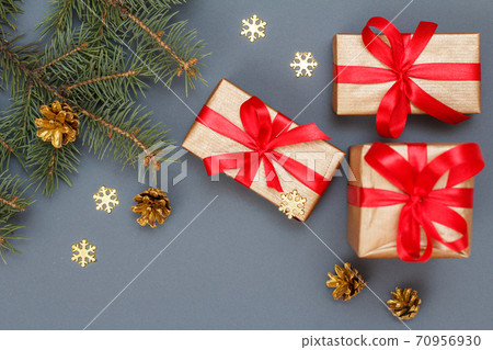 Gift boxes, fir tree branches with cones on gray background Gift boxes, fir tree branches with cones on gray background 70956930