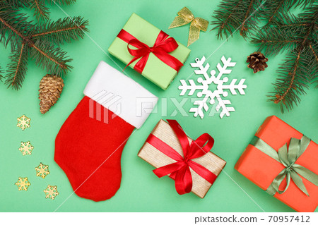 Santa's boot, gift boxes, fir tree branches with cones on green background Santa's boot, gift boxes, fir tree branches with cones on green background 70957412