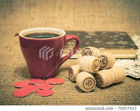 Wooden lotto barrels, cards, chips and cup of coffee on sackcloth. Wooden lotto barrels, cards, chips and cup of coffee on sackcloth. 70957423