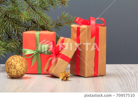 Gift boxes, toy ball and fir tree branch on gray background Gift boxes, toy ball and fir tree branch on gray background 70957510