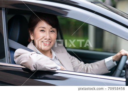 Woman in a suit driving a car 70958456