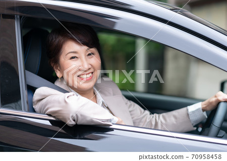 Woman in a suit driving a car 70958458