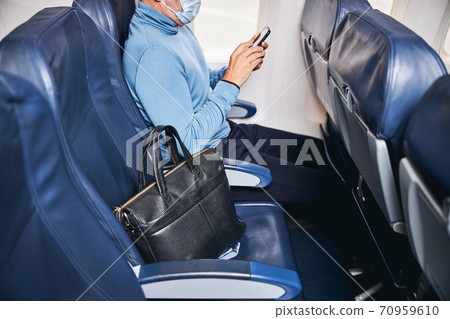 Man reading a text message on the plane 70959610