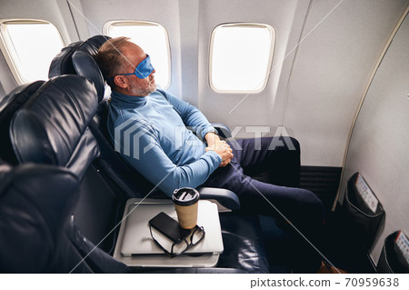 Man in the sleep mask relaxing on the plane Man in the sleep mask relaxing on the plane 70959638